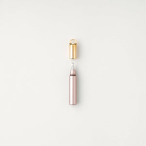 Tom's Studio Field Mouse pen in Blush (soft pink), uncapped with brass loop cap above, on textured white background