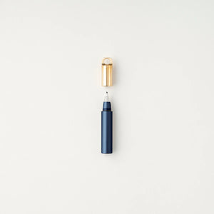 Tom's Studio Field Mouse pen in Midnight (dark navy), uncapped with brass loop cap above, on textured white background