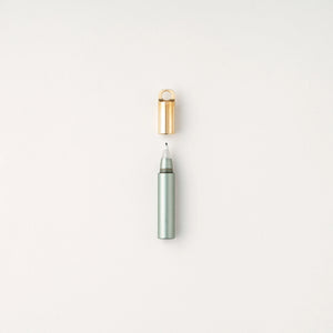 Tom's Studio Field Mouse pen in Sage (soft green), uncapped with brass loop cap above, on textured white background
