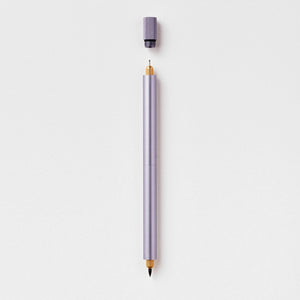 Tom's Studio Lumos Pro Duo in Lilac (pale purple), fineline and brush tips exposed, cap shown above, on textured paper