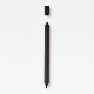 Tom's Studio Lumos Pro Duo in Black, fineline and brush tips exposed, cap shown above, on textured paper