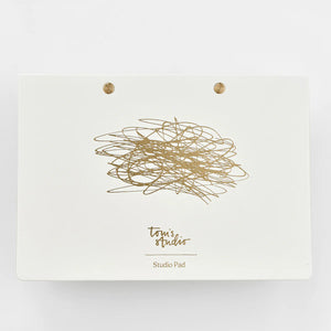 Tom's Studio The Studio Pad A5 in landscape, white cover with gold scribble design, brass studs, and branding